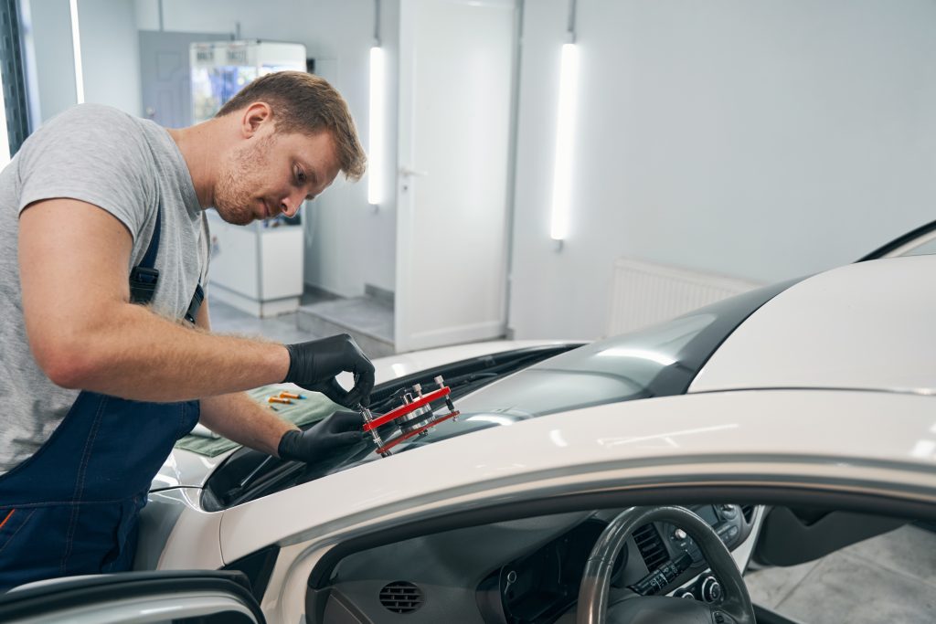  Technician repairing a windshield in a workshop.
