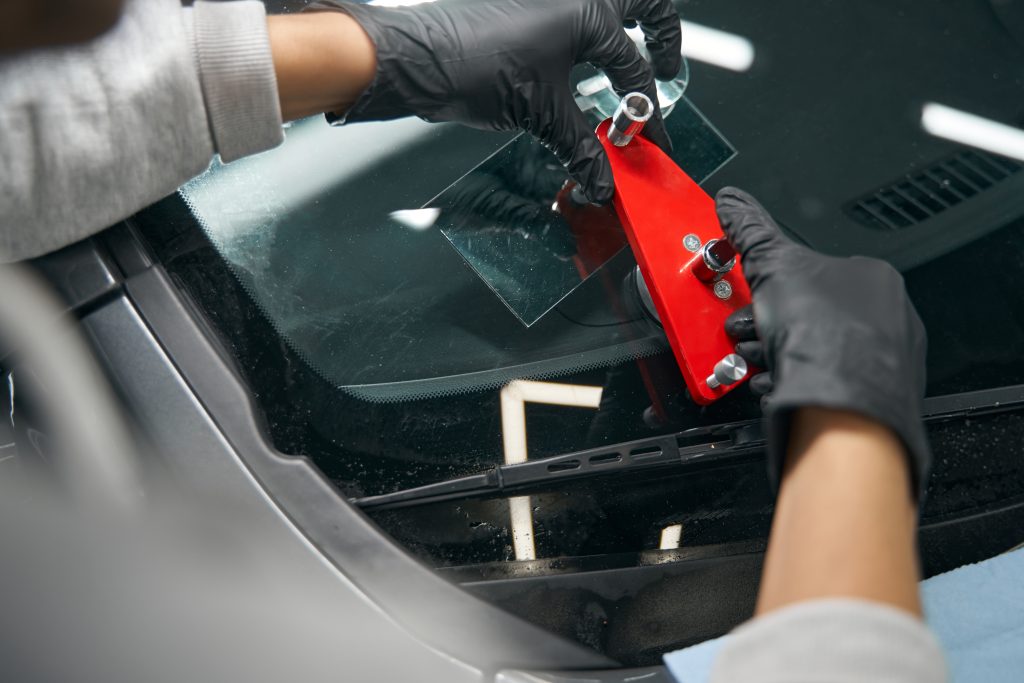 Skilled worker mounting crack repair device on windshield for rock chip repair.