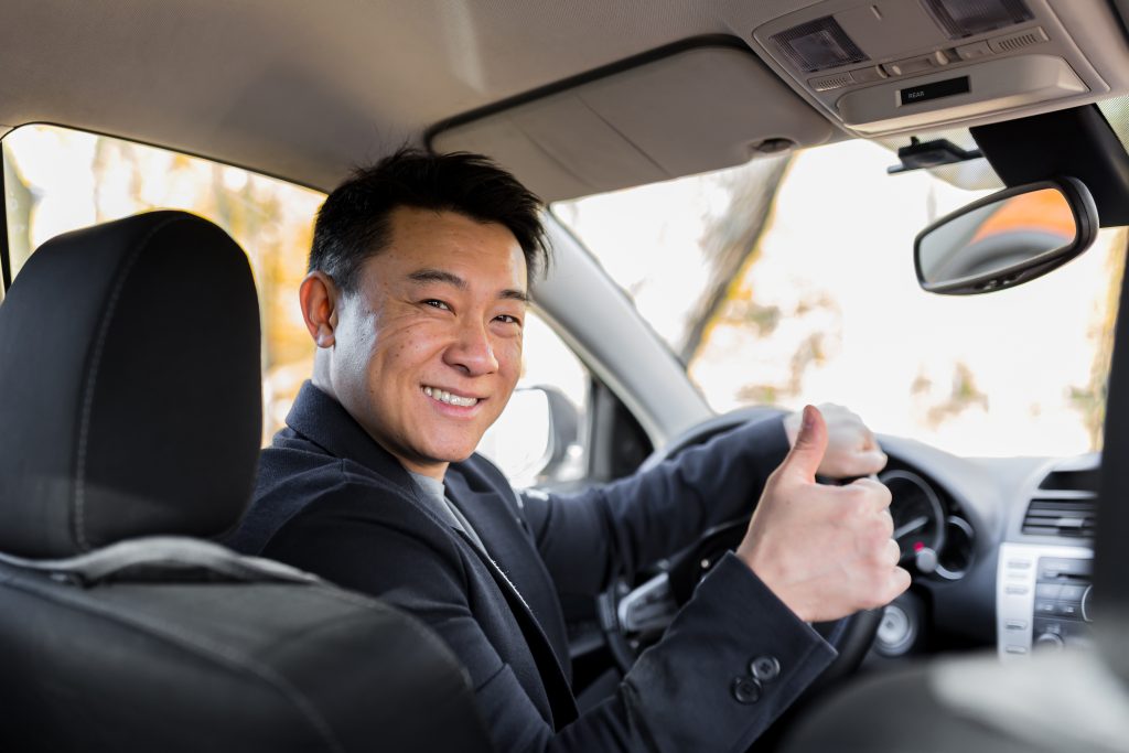  A satisfied driver giving a thumbs-up with an undamaged windshield, indicating contentment with the mobile windshield repair service.